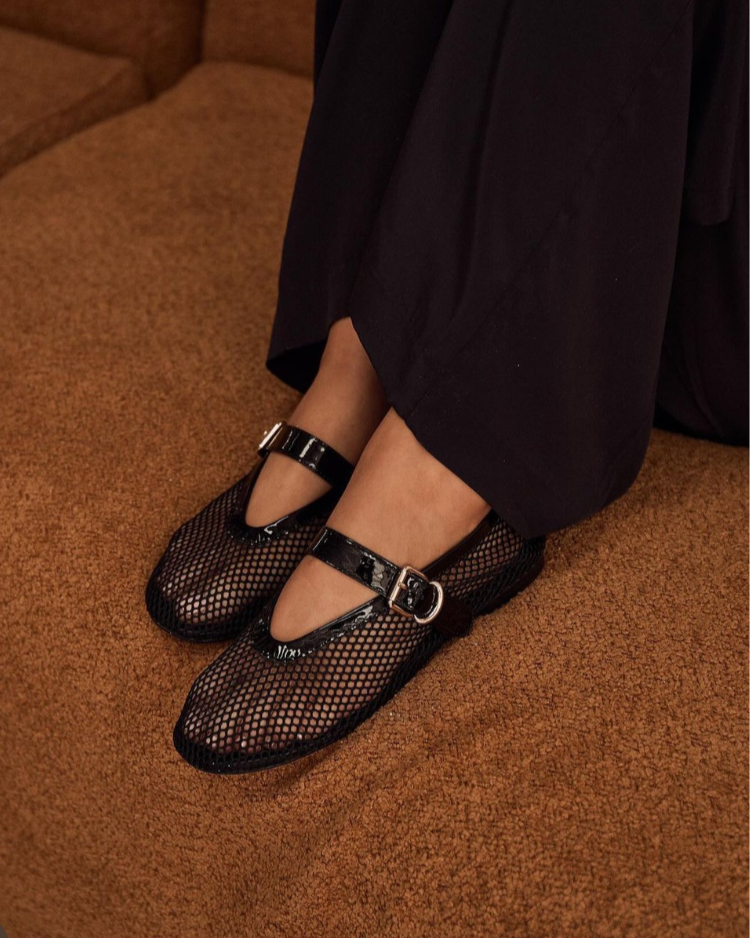 Black mesh shoes with buckles worn by a person on a brown carpet